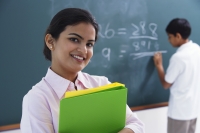 smiling teacher holding notebooks, boy at chalkboard - Alex Mares-Manton