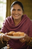 older woman offering food, smiling at camera - Alex Mares-Manton
