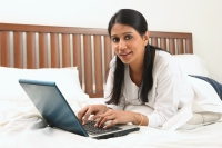 Woman with laptop in bed - Deepak Budhraja