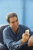 Man with gray hair smiling and checking messages - Manoj Adhikari