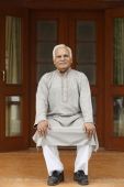 Old man sitting in chair on front porch - Manoj Adhikari