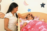 Mom tucking daughter into crib - Deepak Budhraja