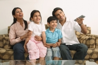 Family watching tv on couch - Deepak Budhraja