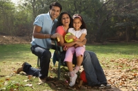 Family in park, girl holding yellow balloon - Deepak Budhraja