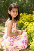Little girl kneeling by yellow flowers - Deepak Budhraja