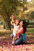 Daughter on mother's lap holding blossom - Deepak Budhraja