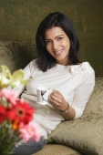 woman holds cup of tea and smiles at camera - Alex Mares-Manton