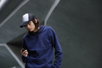 young man checking text messages, wearing cap - Yukmin