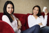 two woman on couch, one with cup in hand - Yukmin