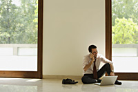 businessman on phone, sitting on floor with computer - Alex Mares-Manton