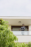 businessman standing at balcony - Alex Mares-Manton
