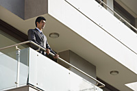businessman standing at balcony - Alex Mares-Manton