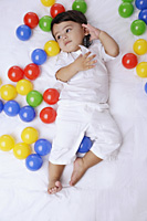 baby boy surrounded by balls, cell phone to ear - Alex Mares-Manton