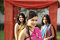 three young women wearing saris standing in front of tent - Alex Mares-Manton