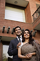 smiling couple, standing in front of home - Alex Mares-Manton