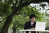 young man in suit, using laptop outdoors - Yukmin