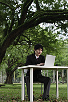 young man in suit, using laptop at a park - Yukmin