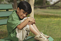 Little boy hugging knees on park bench - Vivek Sharma