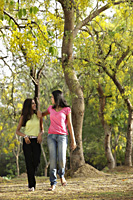 Two teen girls walking in grove of trees - Vivek Sharma