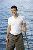 Man standing in lake, holding stick - Yukmin