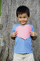 Boy standing by tree holding heart - Yukmin