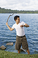 Man throwing stick into lake - Yukmin