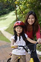 Mother teaching daughter to ride bicycle - Yukmin