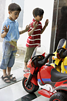 boys looking at toy motorcycles through the shop window - Alex Mares-Manton