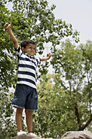 boy standing on rocks with arms up - Alex Mares-Manton