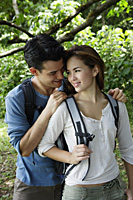 Couple with back packs standing under a tree - Yukmin
