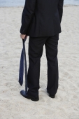 Businessman on beach, holding tie - Yukmin