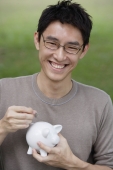 Man putting coin into piggy bank - Yukmin