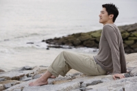 Man sitting on sea shore - Yukmin