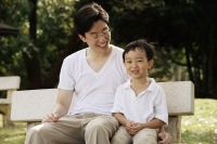 Father and son sitting on park bench - Yukmin