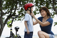 Young woman fastening helmet on boy - Yukmin
