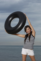 Young woman smiling and holding up inner tube - Yukmin