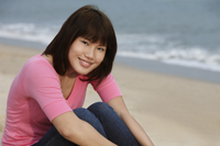 Young woman sitting on beach - Yukmin