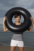 Young woman smiling through middle of inner tube - Yukmin