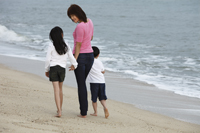 Young woman walking on beach with boy and girl - Yukmin