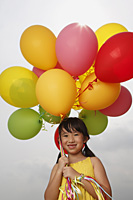 Girl smiling at camera holding balloons. - Yukmin