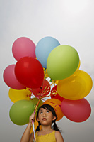 Young girl holding balloons looking up. - Yukmin