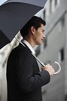 side profile of businessman holding umbrella - Yukmin
