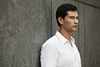 man in white shirt leaning against wall - Yukmin