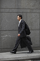 businessman walking holding briefcase, carrying back pack - Yukmin