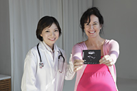 Female doctor with pregnant woman holding sonogram - Yukmin