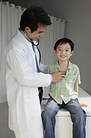 Doctor listening to young boy's heart - Yukmin