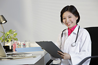 Woman Doctor working at desk and smiling - Yukmin