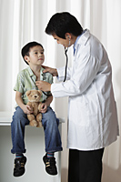 Doctor listening to young boy's heart - Yukmin