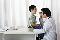 Doctor looking at young boy's mouth - Yukmin