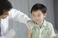 Doctor giving young boy a injection - Yukmin
